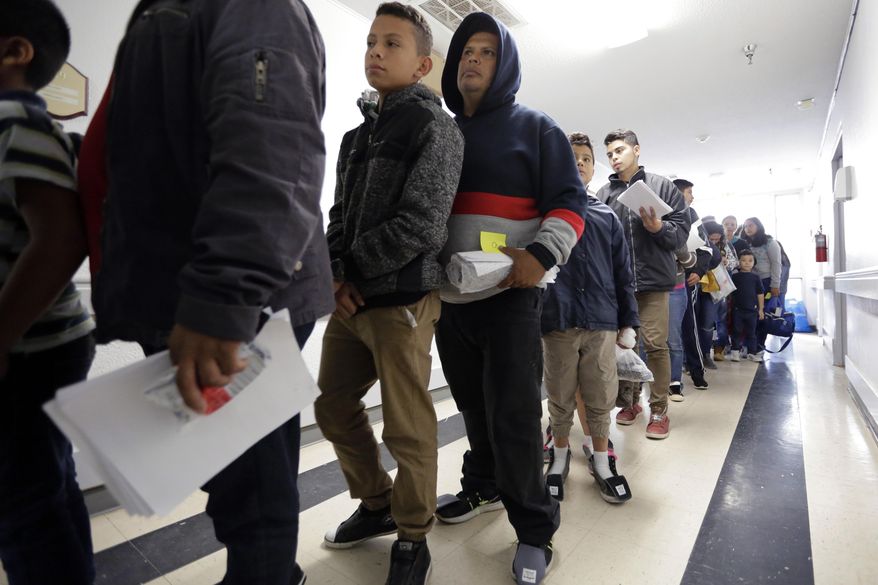 In this Friday, Jan. 11, 2019, file photo, a line of migrants recently released by U.S. immigration authorities waits to check in at the Catholic Charities shelter in McAllen, Texas. (AP Photo/Eric Gay) ** FILE **