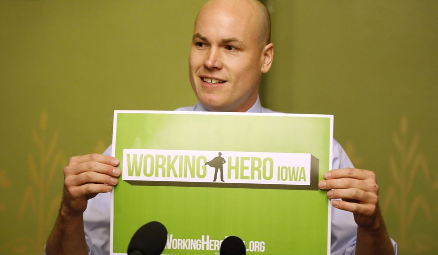 Former Iowa Democratic Congressional candidate J.D. Scholten holds up a sign as he speaks during a news conference, Wednesday, Jan. 23, 2019, at the Statehouse in Des Moines, Iowa. Scholten, a former minor league baseball player who narrowly lost his bid to defeat U.S. Rep. Steve King in Iowa’s 4th Congressional District says he’s keeping his options open for a political future but for now is working to create an Iowa nonprofit organization to help fight poverty.  (AP Photo/Charlie Neibergall)