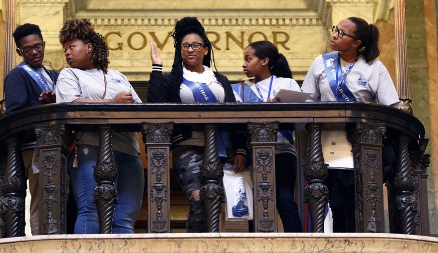 American Cancer Society Cancer Action Network high school student representatives peer over the barrister in front of the Governor's Office at the Capitol in Jackson, Miss., as they try to spot lawmakers to lobby for legislation that would ban people younger than 18 from using tanning beds, Wednesday, Jan. 23, 2019. The students say teenagers put themselves at risk of cancer while tanning for proms or other events. (AP Photo/Rogelio V. Solis)