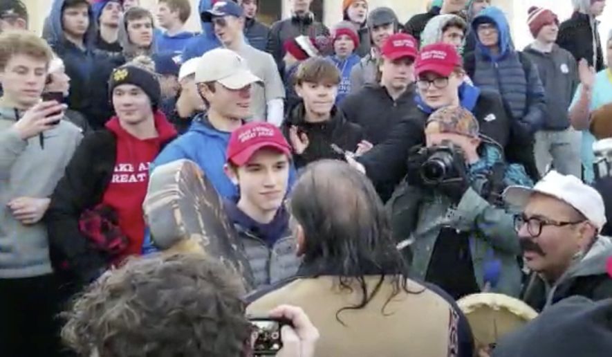 In this Friday, Jan. 18, 2019, file image made from video provided by the Survival Media Agency, Nick Sandmann, wearing a &quot;Make America Great Again&quot; hat, center left, stands in front of Native American elder Nathan Phillips. (Survival Media Agency via AP) ** FILE **