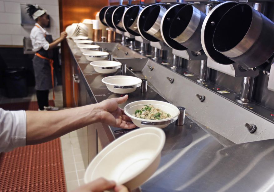 In this May 3, 2018, file photo a worker lifts a lunch bowl off the production line at Spyce, a restaurant that uses a robotic cooking process, in Boston. Robots aren’t replacing everyone, but a quarter of U.S. jobs will be severely disrupted as artificial intelligence accelerates the automation of today’s work, according to a new Brookings Institution report published Thursday, Jan. 24, 2019. (AP Photo/Charles Krupa, File)
