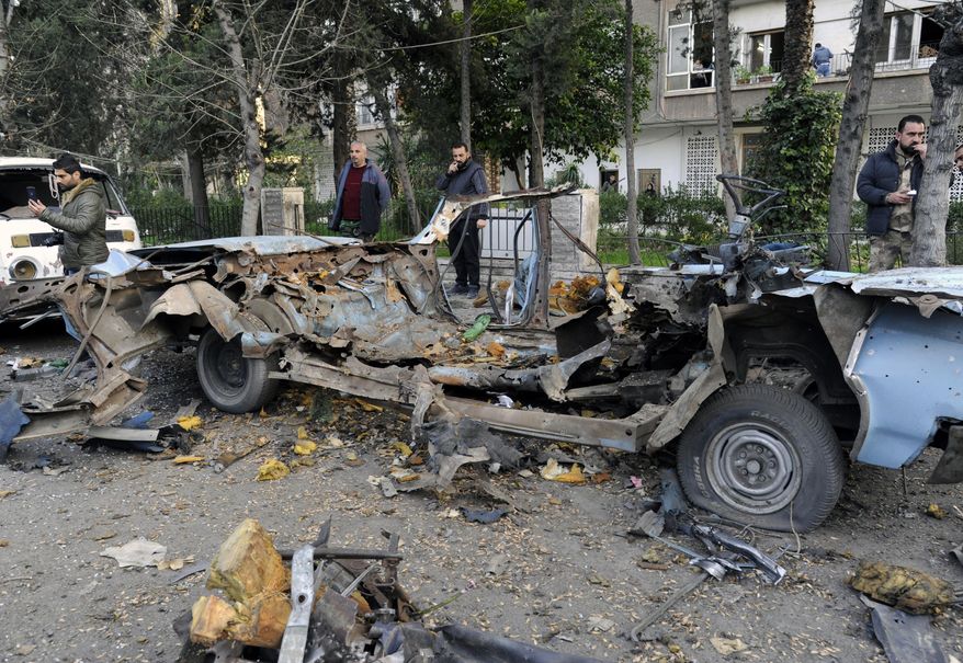 In this photo released by the Syrian official news agency SANA, people gather at the site of an explosion in the Adawi neighborhood of Damascus, Syria, Thursday, Jan. 24, 2019. Syrian state media reported that the bomb caused property damage but no casualties. The Russian Embassy is located several hundred meters (yards) away. (SANA via AP)