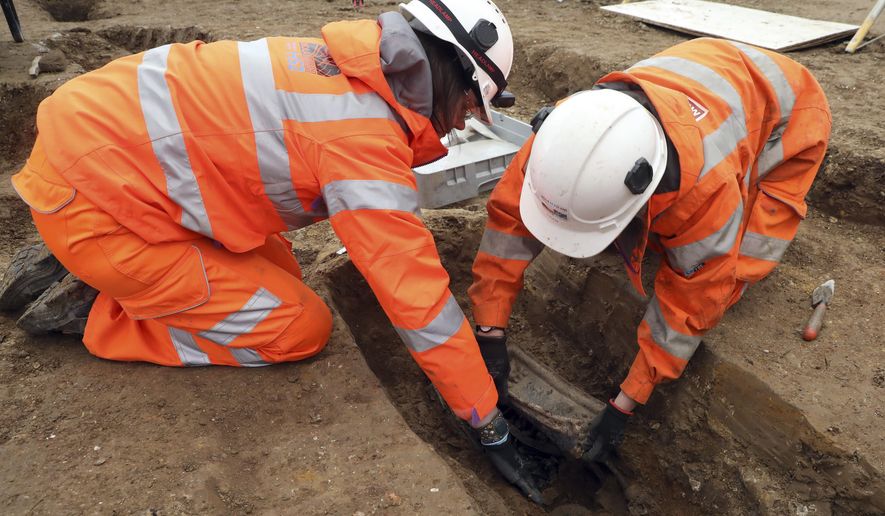 An image taken on Jan. 18, 2019 and issued by HS2 shows archeologists removing the lead plate placed on top of the coffin of Captain Matthew Flinders at the archaeological excavation and research works at St James's Gardens in Euston, London. The remains of Captain Flinders, a noted Royal Navy explorer, who led the first circumnavigation of Australia have been found by archeologists excavating a burial ground where a railway station is planned. The archeologists identified the remains of Flinders by the lead plate placed on top of his coffin. (James O. Jenkins/HS2 via AP)