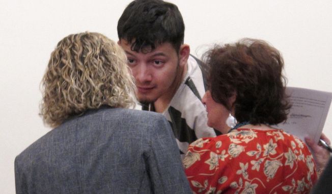 Wilber Ernesto Martinez-Guzman, 19, of El Salvador, listens to his public defender and interpreter during his initial appearance in Carson City Justice Court, Thursday, Jan. 24, 2019, in Carson City, Nev. Martinez-Guzman was arraigned on 36 felonies including two dozen weapon charges. He's a suspect in a series of four homicides earlier this month in Reno and south of Carson City in rural Gardnerville. Prosecutors say additional charges are pending. (AP Photo/Scott Sonner)