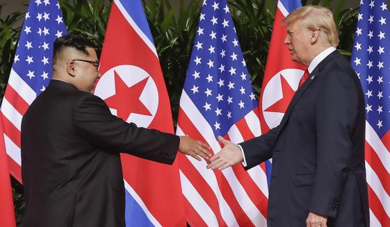 FILE - In this June 12, 2018, file photo, U.S. President Donald Trump reaches to shake hands with North Korea leader Kim Jong Un at the Capella resort on Sentosa Island in Singapore. (AP Photo/Evan Vucci, File)