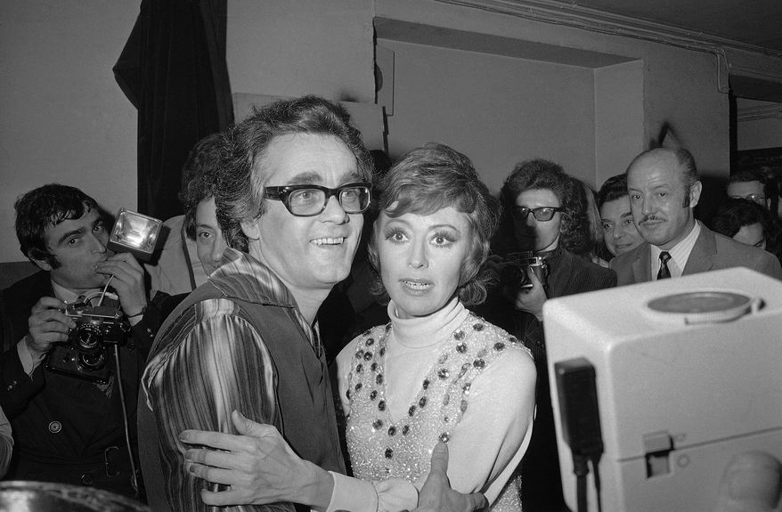 FILE - In this Jan. 20, 1972 file picture French-born Italian singer, dancer and actress Caterina Valente, right, embraces Franco-Armenian musical composer, arranger, conductor and pianist Michel Legrand after their show at the Olympia in Paris, France. Oscar-winning composer and pianist Michel Legrand, whose hits included the score for "The Umbrellas of Cherbourg" and the song "The Windmills of Your Mind" and who left a lasting imprint on France's musical universe, has died at age 86. (AP Photo/Michel Lipchitz, File)