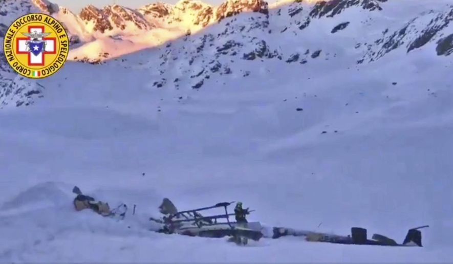 A rescuer stands next to the debris of an helicopter after a midair collision between a small tourist airplane and a helicopter carrying skiers to a glacier in the northwestern region of Val d'Aosta, Friday, Jan 25, 2019. Italian alpine rescue officials say five people have been killed in the crash that took place over the Rutor Glacier. (Soccorso Alpino e Speleologico via AP)