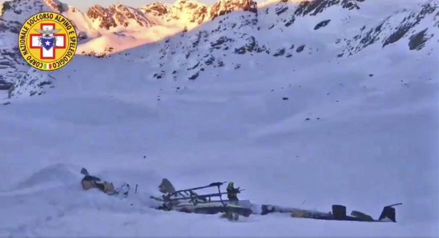 A rescuer stands next to the debris of an helicopter after a midair collision between a small tourist airplane and a helicopter carrying skiers to a glacier in the northwestern region of Val d'Aosta, Friday, Jan 25, 2019. Italian alpine rescue officials say five people have been killed in the crash that took place over the Rutor Glacier. (Soccorso Alpino e Speleologico via AP)