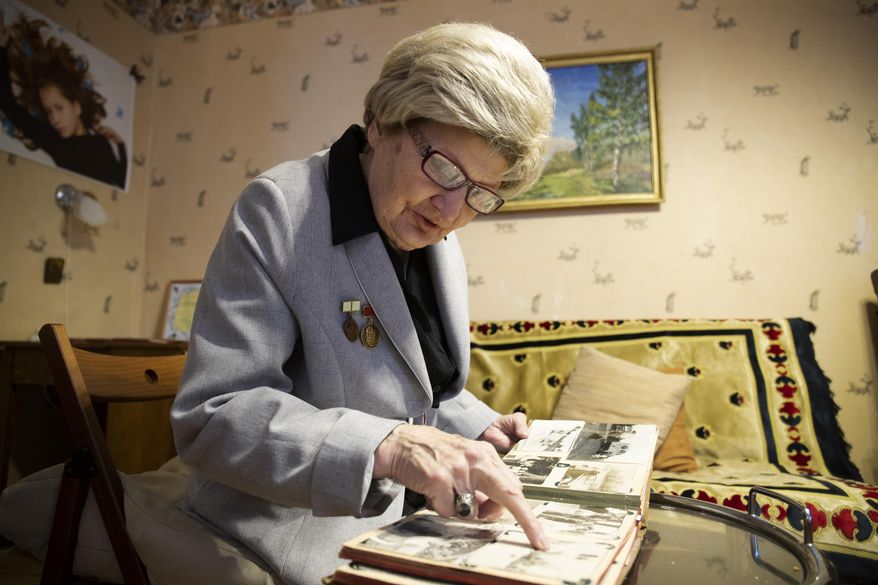 In this Wednesday, Jan. 23, 2019 photo, Tamara Chernykh, 81, a survivor of the Nazi siege of Leningrad during World War II, looks at her photo album in St. Petersburg, Russia. The Nazi siege of Leningrad lasted nearly 2 and a half years until the Soviet Army drove the Nazi troops away on Jan. 27, 1944. Estimates of the death toll vary, but historians agree that more than one million Leningrad residents died of hunger and air and artillery bombardment in one of the most horrifying episodes of World War II. (AP Photo/Dmitri Lovetsky)