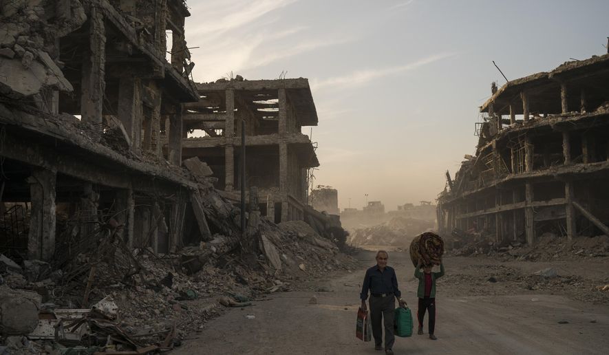In this Nov. 15, 2017 file photo, Haider, left, and Abdullah carry belongings they collected from their damaged house to wash before returning to live in the Old City of Mosul, Iraq. For centuries, residents of Mosul have spoken a unique form of Arabic enriched by the Iraqi city’s long history as a crossroads of civilization, a singsong dialect that many now fear will die out after years of war and displacement. (AP Photo/Felipe Dana, File)