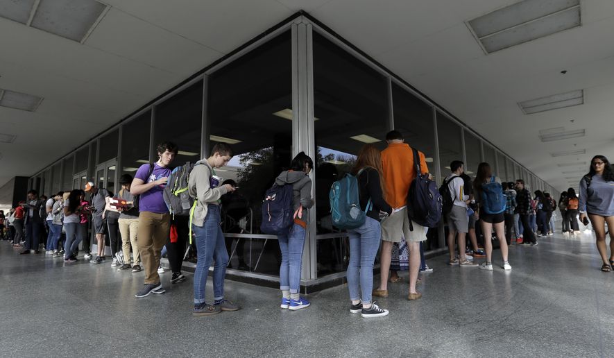 FILE - In this March 6, 2018 file photo, a line of mostly students wait to vote at a Texas primary election polling site on the University of Texas campus in Austin, Texas. The ACLU and other groups slammed Texas elections officials who say they found 95,000 people identified as non-citizens who had a matching voter registration record. Texas Attorney General Ken Paxton now says many of them could have become citizens and voted legally.(AP Photo/Eric Gay, File)