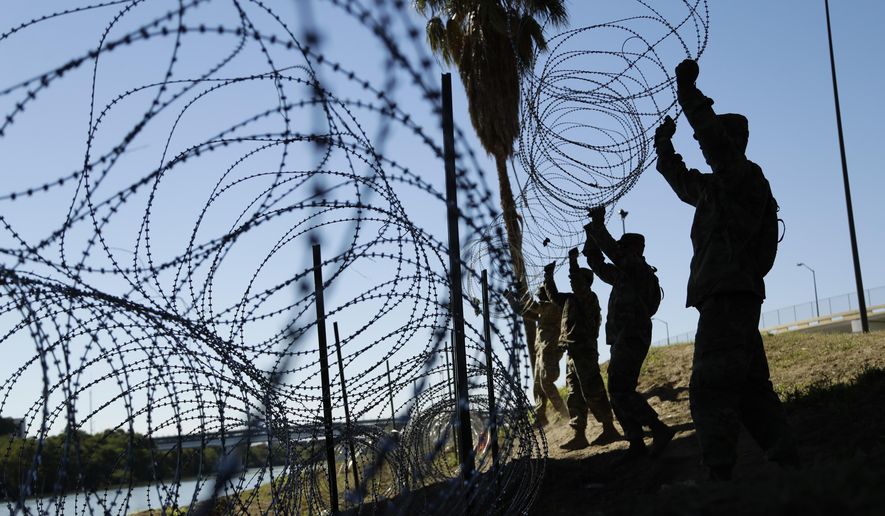 In this file photo, members of the U.S. military install multiple tiers of concertina wire along the banks of the Rio Grande near the Juarez-Lincoln Bridge at the U.S.-Mexico border in Laredo, Texas. (AP Photo/Eric Gay, File)  **FILE**
