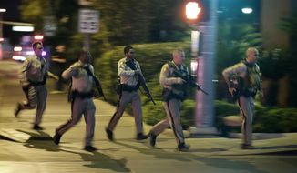 FILE - In this Oct. 1, 2017, file photo, police run for cover at the scene of a shooting near the Mandalay Bay resort and casino on the Las Vegas Strip in Las Vegas. In a report released Tuesday, Jan. 29, 2019, the FBI concluded its investigation into the deadliest mass shooting in modern U.S. history without determining a motive. After nearly 16 months, the agency says it can&#39;t determine why gunman Stephen Paddock killed 58 people and injured nearly 900 others in October 2017. (AP Photo/John Locher, File)