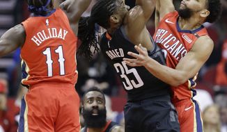 Houston Rockets forward Kenneth Faried, center, shoots as New Orleans Pelicans guard Jrue Holiday (11) and center Jahlil Okafor defend during the first half of an NBA basketball game Tuesday, Jan. 29, 2019, in Houston. (AP Photo/Eric Christian Smith)