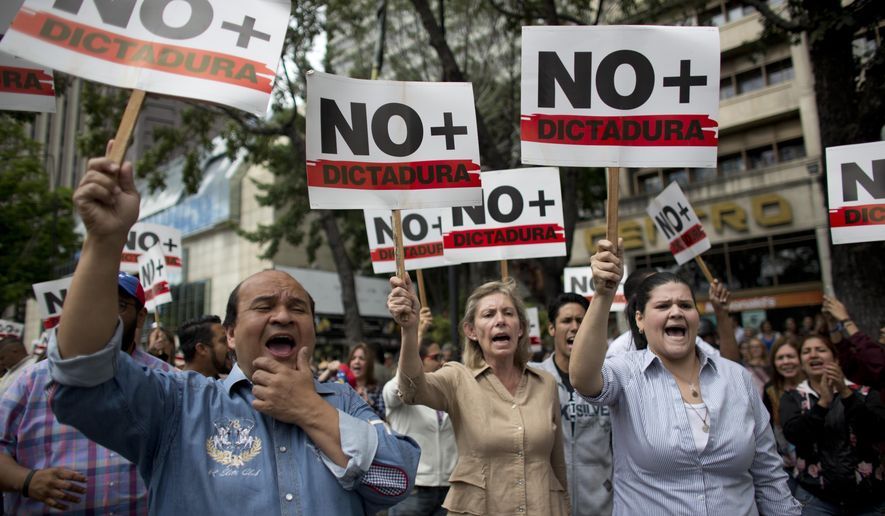 People holding signs with a message that reads in Spanish: "No more dictatorship" take part in a walkout against President Nicolas Maduro, in Caracas, Venezuela, Wednesday, Jan. 30, 2019. Doctors in scrubs, businessmen in suits and construction workers in jeans gathered on the streets of Venezuela's capital Wednesday, demanding Maduro step down from power in a walkout organized by the nation's reinvigorated opposition to ratchet up pressure on the embattled president. (AP Photo/Ariana Cubillos)