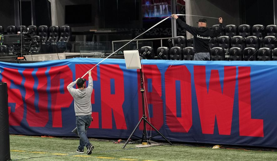 Workers use a tape measure as they hang a sign inside Mercedes-Benz Stadium for the NFL Super Bowl 53 football game Tuesday, Jan. 29, 2019, in Atlanta. (AP Photo/David J. Phillip)