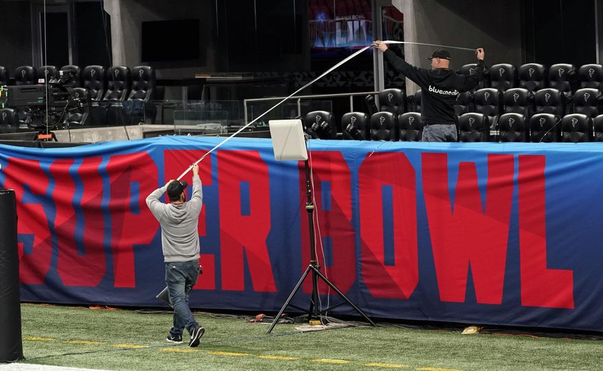 Workers use a tape measure as they hang a sign inside Mercedes-Benz Stadium for the NFL Super Bowl 53 football game Tuesday, Jan. 29, 2019, in Atlanta. (AP Photo/David J. Phillip)