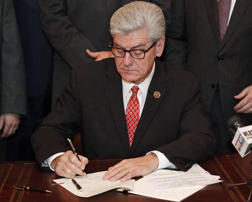 Gov. Phil Bryant, signs the Mississippi Broadband Enabling Act, at the Capitol in Jackson, Miss., Wednesday Jan. 30, 2019. The measure allows Mississippi's 25 electric cooperatives to form subsidiaries to offer broadband internet service, removing a ban on the member-owned utilities getting into other businesses. (AP Photo/Rogelio V. Solis)