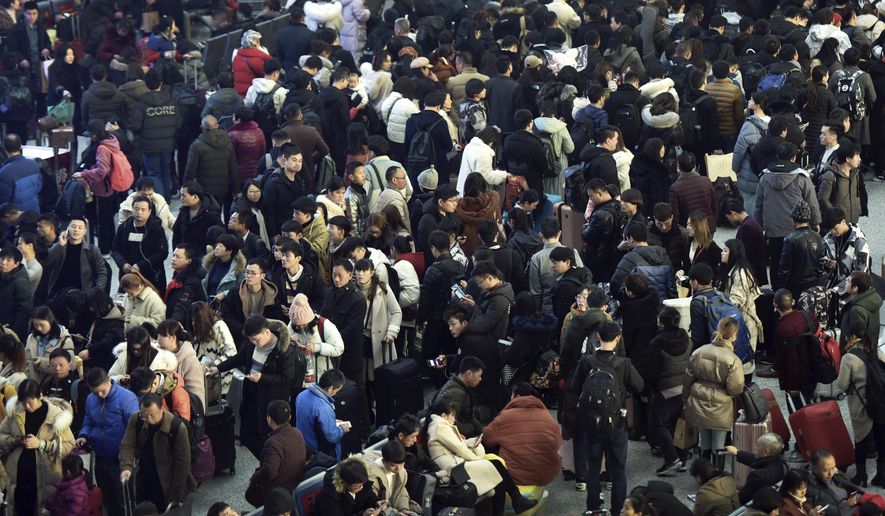 In this Jan. 28, 2019, photo, Chinese travelers wait for their trains at a railway station in Hangzhou in east China's Zhejiang province. The world's largest annual migration has began in China with millions of Chinese are traveling to their hometowns to celebrate the Lunar New Year on Feb. 5 this year which marks the Year of the Pig on the Chinese zodiac. (Chinatopix via AP)