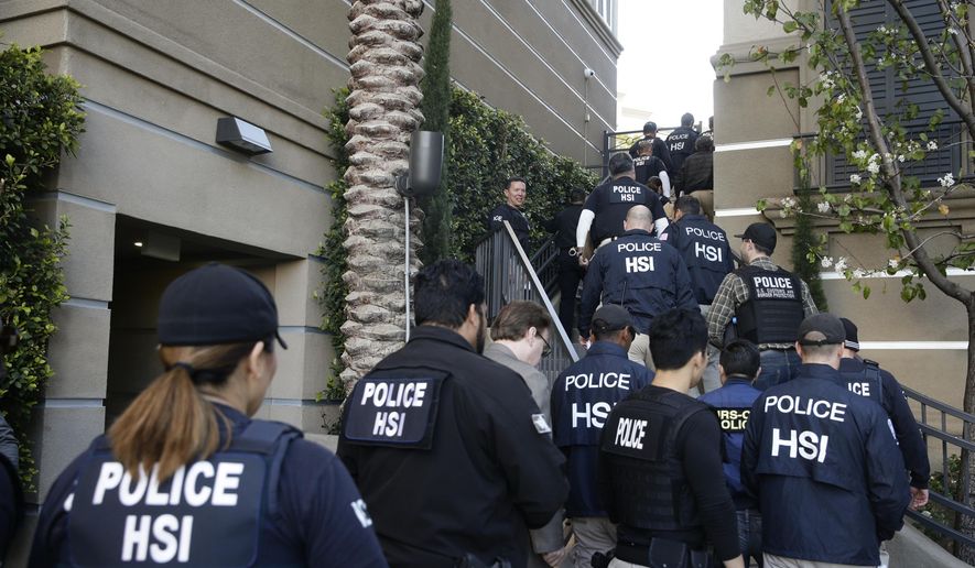 In this March 3, 2015, file photo, federal agents enter an upscale apartment complex where authorities say a birth tourism business charged pregnant women $50,000 for lodging, food and transportation, in Irvine, Calif. (AP Photo/Jae C. Hong, File)
