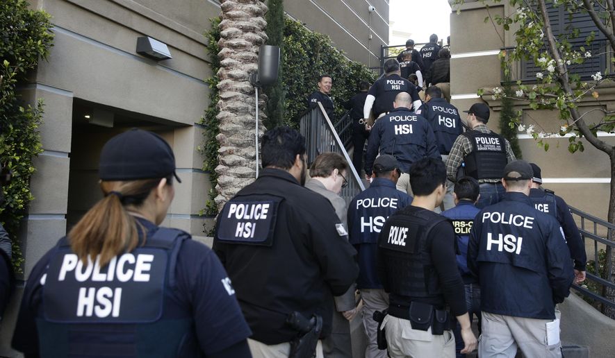 In this March 3, 2015, file photo, federal agents enter an upscale apartment complex where authorities say a birth tourism business charged pregnant women $50,000 for lodging, food and transportation, in Irvine, Calif. (AP Photo/Jae C. Hong, File)
