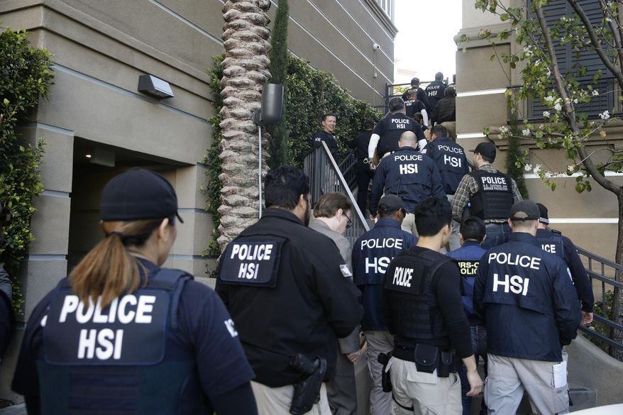 In this March 3, 2015, file photo, federal agents enter an upscale apartment complex where authorities say a birth tourism business charged pregnant women $50,000 for lodging, food and transportation, in Irvine, Calif. (AP Photo/Jae C. Hong, File)