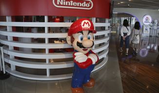 This June 19, 2018, photo, visitors walk around a figure of Super Mario of Nintendo at Panasonic center in Tokyo. Nintendo, the Japanese video game maker behind the Super Mario and Pokemon franchises, is reporting a 25 percent jump in fiscal third-quarter profit, boosted by the popularity of games for its Switch console. (AP Photo/Koji Sasahara)