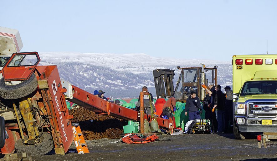 This Thursday, Jan. 31, 2019 photo shows Homer Volunteer Fire Department emergency medical technicians treating a person injured when a crane tipped over in the buoy yard of the U.S. Coast Guard Cutter Hickory at the Pioneer Dock on the Homer Spit in Homer, Alaska. (Michael Armstrong/Homer News via AP)