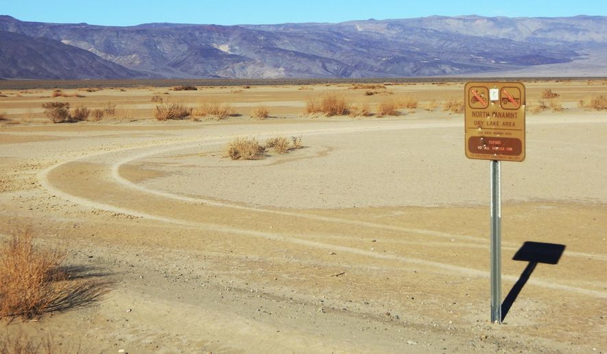 This undated photo provided by the U.S. National Park Service shows vehicle tracks beyond a sign banning vehicles in the North Panamint dry lake area during the recent federal government shutdown in an area of Death Valley National Park, Calif. National parks across the United States are scrambling to clean up and repair damage caused by visitors and storms during the government shutdown while bracing for another possible closure ahead of the usually busy President's Day weekend. (National Park Service via AP)