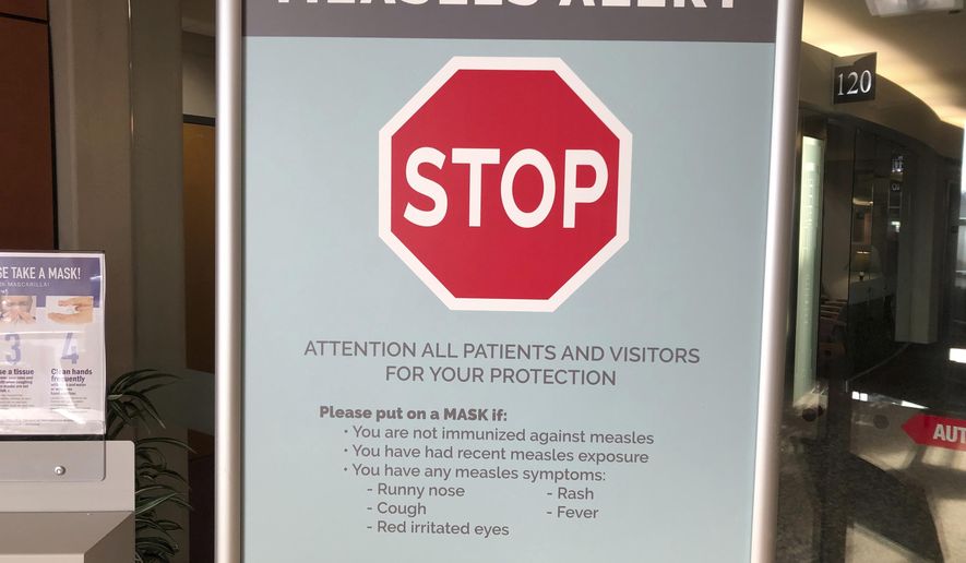 FILE - In this Jan. 30, 2019 file photo signs posted at The Vancouver Clinic in Vancouver, Wash., warn patients and visitors of a measles outbreak. A measles outbreak near Portland, Ore., has revived a bitter debate over so-called personal belief exemptions to childhood vaccinations. Four percent of Washington secondary school students have non-medical vaccine exemptions. (AP Photo/Gillian Flaccus,File)
