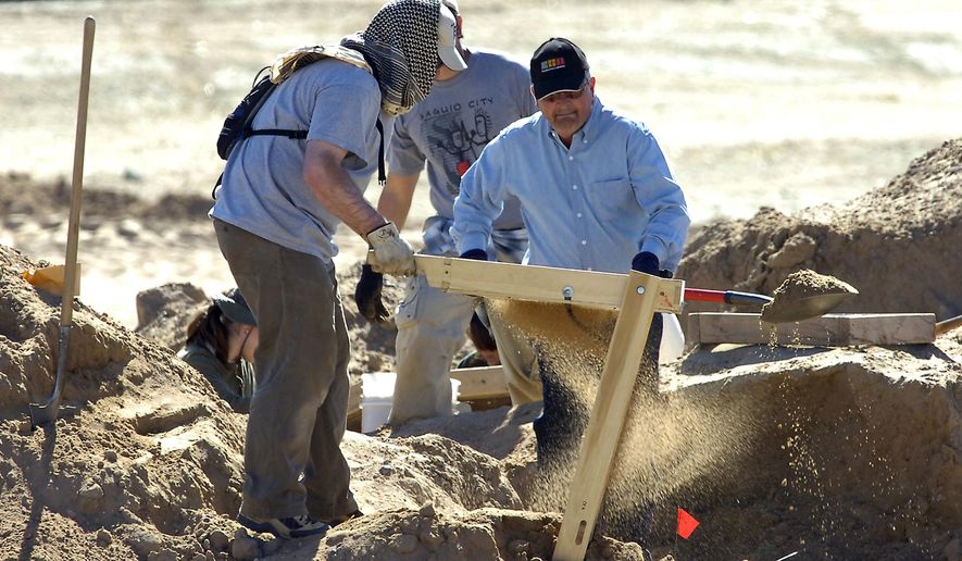 FILE - In this Feb. 25, 2009 file photo, investigators search for human remains at a 100-acre site in Albuquerque, N.M. A decade ago, Albuquerque police began unearthing the remains of 11 women and an unborn child found buried on the city's West Mesa, marking the start of a massive homicide investigation that has yet to be resolved. On the 10th anniversary of the cold case, a small group of advocates and community members plan to gather Saturday, Feb. 2, 2019, near the 2009 crime scene to remember the victims and call for more protections for marginalized and vulnerable women in New Mexico's largest city. (Pat Vasquez-Cunningham/The Albuquerque Journal via AP, File)