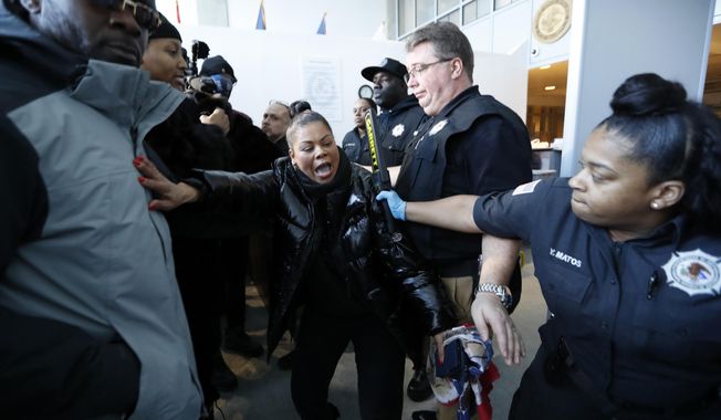 Corrections officers restrain a woman, center, who was among dozens of family members of prisoners and protesters objecting to conditions in the Metropolitan Detention Center, a federal prison in the Brooklyn borough of New York, Sunday, Feb. 3, 2019. (AP Photo/Kathy Willens)