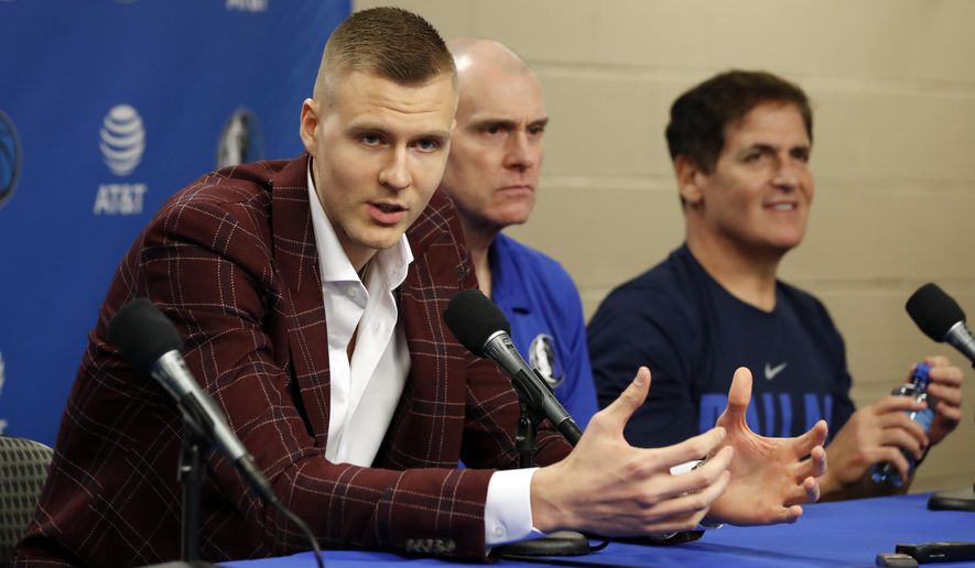 Newly acquired player Kristaps Porzingis, left, responds to questions as head coach Rick Carlisle, center, and team owner Mark Cuban, right, listen during a news conferences where the newly acquired players were introduced in Dallas, Monday, Feb. 4, 2019. (AP Photo/Tony Gutierrez)