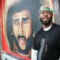 Artist Fabian &amp;quot;Occasional Superstar&amp;quot; Williams stands in front of a Colin Kaepernick-themed mural on Monday, Feb. 4, 2019, in Atlanta. Several such murals were hastily painted over the weekend across the Super Bowl host town in protest after one that had stood for two years was abruptly demolished on the eve of the big game. (AP Photo/ Ron Harris)
