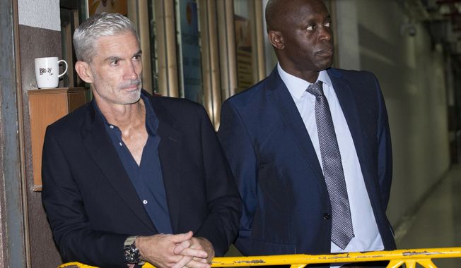 Former Australian soccer national team member Craig Foster, left, and Vice President of FIFPro Francis Awaritefe wait to meet detained Bahraini soccer player Hakeem al-Araibi as he arrives at the criminal court in Bangkok, Thailand, Monday, Feb. 4, 2019. Al-Araibi who has refugee status in Australia pleaded outside a Bangkok court on Monday for Thailand to not send him home to Bahrain, which is seeking his extradition to serve a prison sentence for a crime he denies. (AP Photo/Sakchai Lalit)