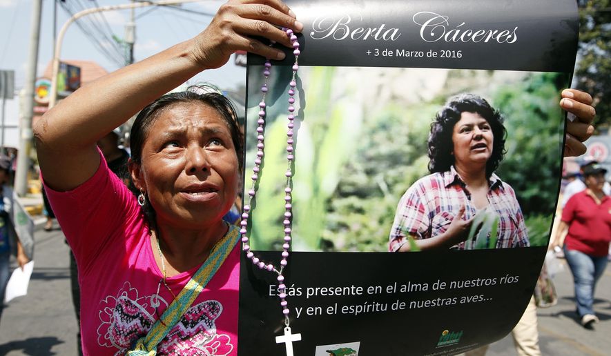 FILE - In this March 16, 2016 file photo, a woman holds up a poster with a photo of slain environmental leader Berta Caceres, during a protest march in Tegucigalpa, Honduras. Honduran prosecutors said on Tuesday, Feb. 5, 2019, that they plan to bring charges against Roberto David Castillo Mejia, a former executive who they allege was a mastermind behind the murder of environmental activist Berta Caceres. (AP Photo/Fernando Antonio, File)