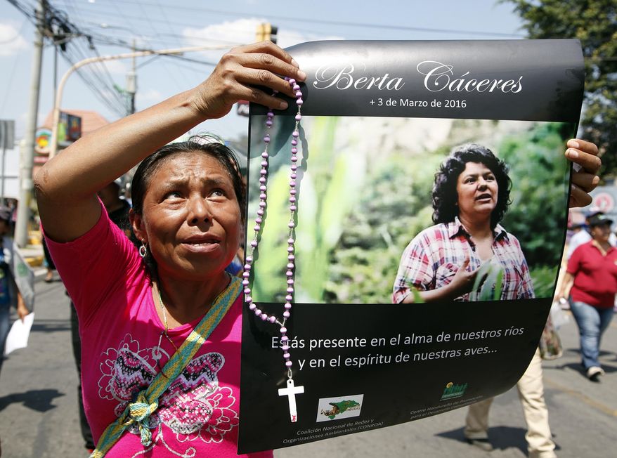 FILE - In this March 16, 2016 file photo, a woman holds up a poster with a photo of slain environmental leader Berta Caceres, during a protest march in Tegucigalpa, Honduras. Honduran prosecutors said on Tuesday, Feb. 5, 2019, that they plan to bring charges against Roberto David Castillo Mejia, a former executive who they allege was a mastermind behind the murder of environmental activist Berta Caceres. (AP Photo/Fernando Antonio, File)