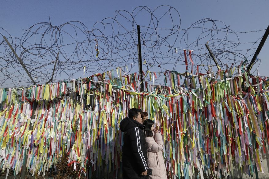 A South Korean family pose in front of ribbons placed on a barbed wire fence with messages wishing for the reunification of the two Koreas as they visit the border to celebrate the Lunar New Year at the Imjingak Pavilion, near the demilitarized zone of Panmunjom, in Paju, South Korea, Tuesday, Feb. 5, 2019. (AP Photo/Ahn Young-joon) **FILE**