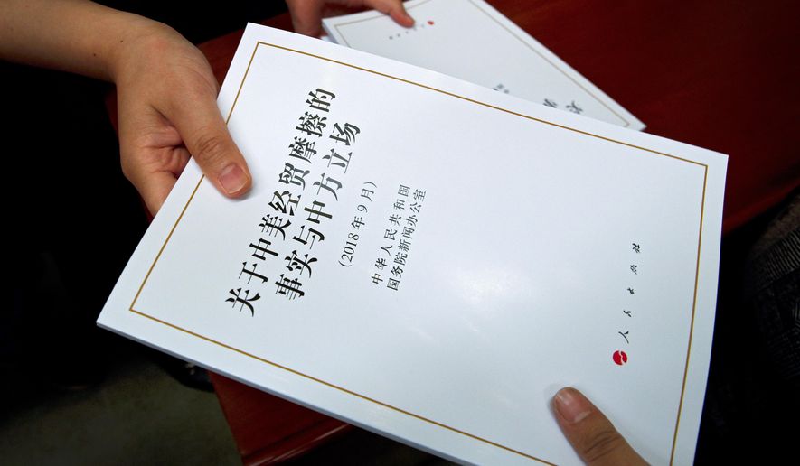 FILE - In this Sept. 25, 2018, file photo, a government officer distributes copies of a report on "the Facts and China's Position on China-U.S. Trade Friction" to journalists during a press conference at the State Council Information Office in Beijing. (AP Photo/Andy Wong, File)