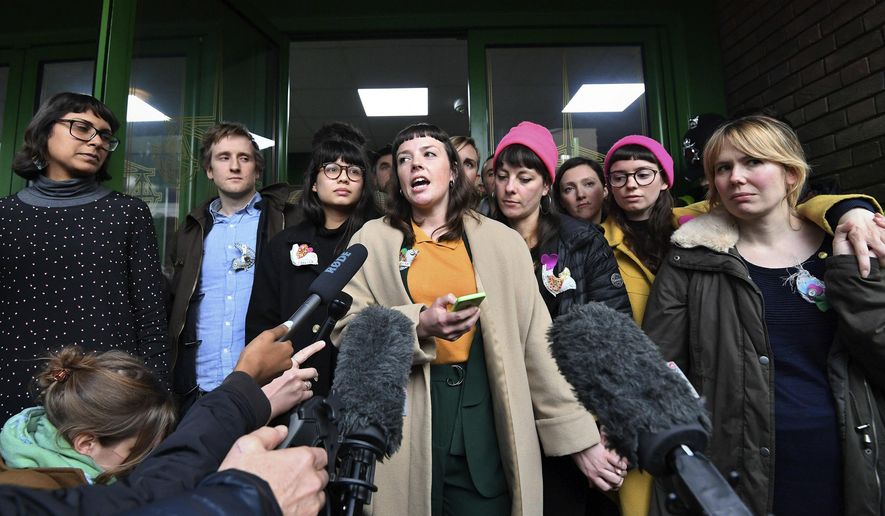 Lyndsay Burtonshaw, center, one of the 'Stansted 15' talks to the media outside Chelmsford Crown Court in Essex, England, Wednesday, Feb. 6, 2019. Fifteen protesters who locked themselves together around a plane at London's Stansted Airport to stop migrants being deported have been spared prison sentences. He gave three protesters suspended jail terms and sentenced 12 to community service. (John Stillwell/PA via AP)