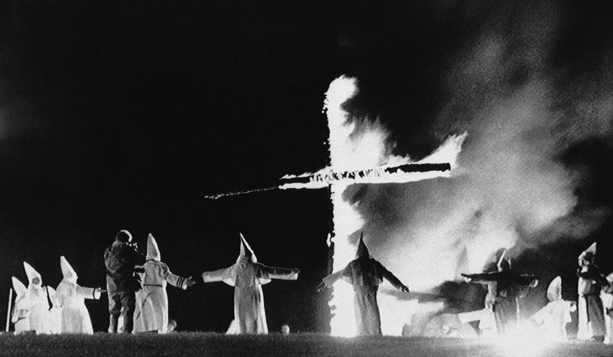 In this Sept. 27, 1987, file photo, the Invisible Empire, Ku Klux Klan members wearing traditional robes form a circle around a burning cross in Rumford, Maine. (AP Photo/Scott Perry, File)
