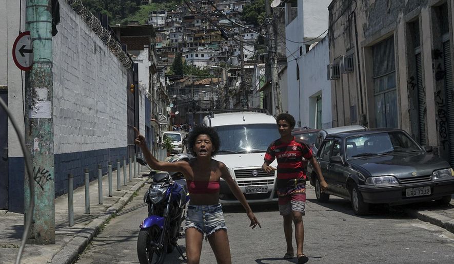 A woman yells that the police is going to execute several alleged traffickers during an operation conducted at Santa Teresa neighborhood in Rio de Janeiro, Brazil, Friday, Feb. 8, 2019. Law enforcement officials in Brazil's second largest city say that at least 11 suspected drug traffickers were killed in a shootout with police in a slum located in the bohemian Santa Teresa neighborhood. (AP Photo/Carson Gardiner)