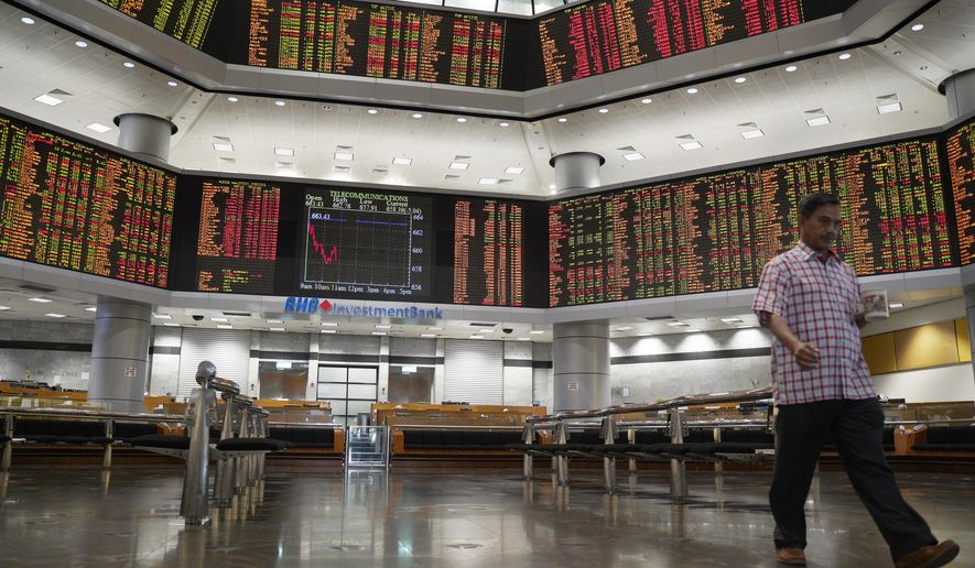 An investor walks in front of private stock trading boards at a private stock market gallery in Kuala Lumpur, Malaysia, Friday, Feb. 8, 2019. Asian markets tumbled on Friday after U.S. President Donald Trump said he doesn’t plan to meet Chinese leader Xi Jinping before a tariffs ceasefire ends in March. (AP Photo/Yam G-Jun)