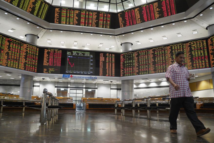 An investor walks in front of private stock trading boards at a private stock market gallery in Kuala Lumpur, Malaysia, Friday, Feb. 8, 2019. Asian markets tumbled on Friday after U.S. President Donald Trump said he doesn’t plan to meet Chinese leader Xi Jinping before a tariffs ceasefire ends in March. (AP Photo/Yam G-Jun)