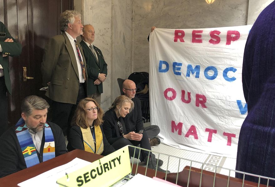 Religious leaders demonstrating against Utah lawmakers' efforts to scale back a voter-approved expansion of Medicaid sit in front of the entrance to the Utah House of Representatives singing protest songs as legislators debate the bill in Salt Lake City, Friday, Feb. 8, 2019. Counter protesters in favor of the bill are also on hand in Salt Lake City. (AP photo/Lindsay Whitehurst)
