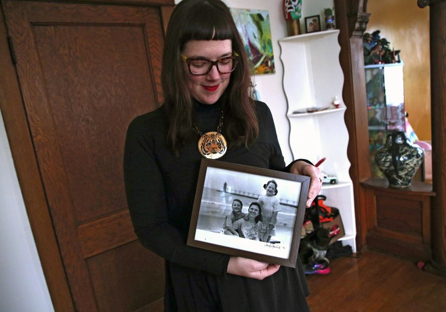 In this Jan. 20, 2019 photo, Morgan Richardson holds a photo of herself, her twin sister Lauren, left, and mother Deborah in Chicago. Richardson, whose biological father was an anonymous sperm donor has discovered via a DNA testing service that she has 15 half siblings. (Terrence Antonio James/Chicago Tribune via AP)