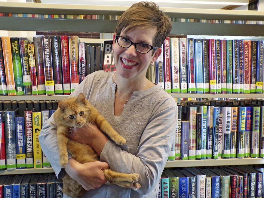 In this Feb. 1, 2019 photo, library director Mara Edler poses with cat Rosie at The Gutekunst Public Library in State Center, Iowa. (Sara Jordan-Heintz/The Times-Republican via AP)