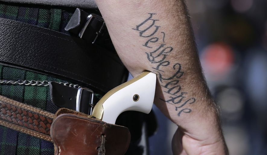 FILE - In this Jan. 26, 2015 file photo, a supporter of open carry gun laws, wears a pistol as he prepares for a rally in support of open carry gun laws at the Capitol, in Austin, Texas. Texas is still sorting out where firearms are allowed, and where they're not, more than a year after Republican Gov. Greg Abbott signed a suite of laws that vastly expanded gun rights. (AP Photo/Eric Gay, File)