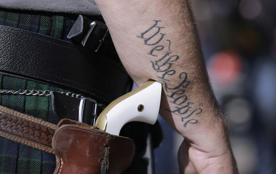 FILE - In this Jan. 26, 2015 file photo, a supporter of open carry gun laws, wears a pistol as he prepares for a rally in support of open carry gun laws at the Capitol, in Austin, Texas. Texas is still sorting out where firearms are allowed, and where they're not, more than a year after Republican Gov. Greg Abbott signed a suite of laws that vastly expanded gun rights. (AP Photo/Eric Gay, File)