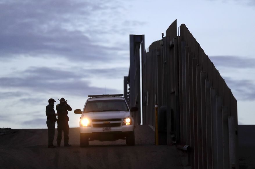 In this Wednesday, Nov. 21, 2018, file photo, United States Border Patrol agents stand by a vehicle near one of the border walls separating Tijuana, Mexico, and San Diego. (AP Photo/Gregory Bull, File)